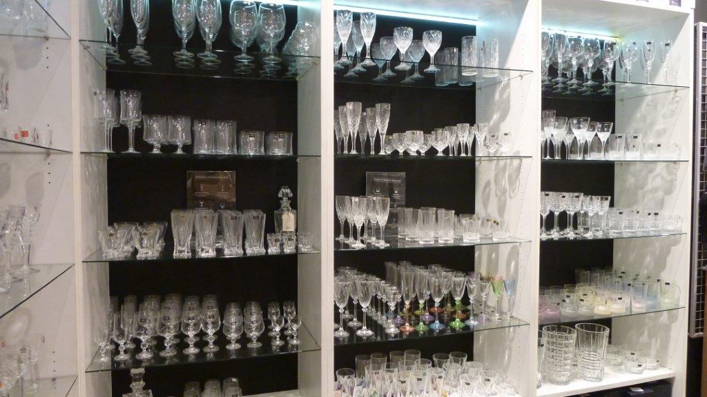 В магазине на витрину выставили наборы бокалов. Выкладка стеклянных товаров. Выкладка стеклянной посуды. Витрина магазина посуды. Выкладка посуды в магазине.